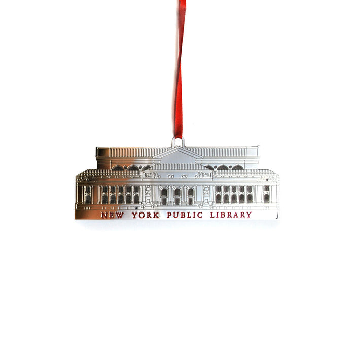 A metal holiday ornament in the shape of the New York Public Library building, with a silver finish, and a red ribbon.