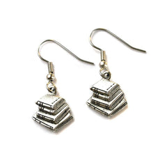 A pair of silver book stack earrings dangle from ear wires against a white background.